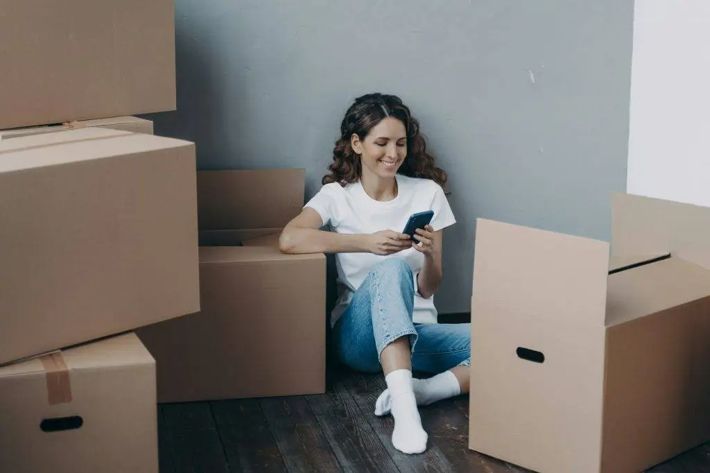 Settling In: Essential Tips for Making Your New House Feel Like Home 1 Happy girl uses phone apps, choosing relocation service, answers her mover online. Easy moving day