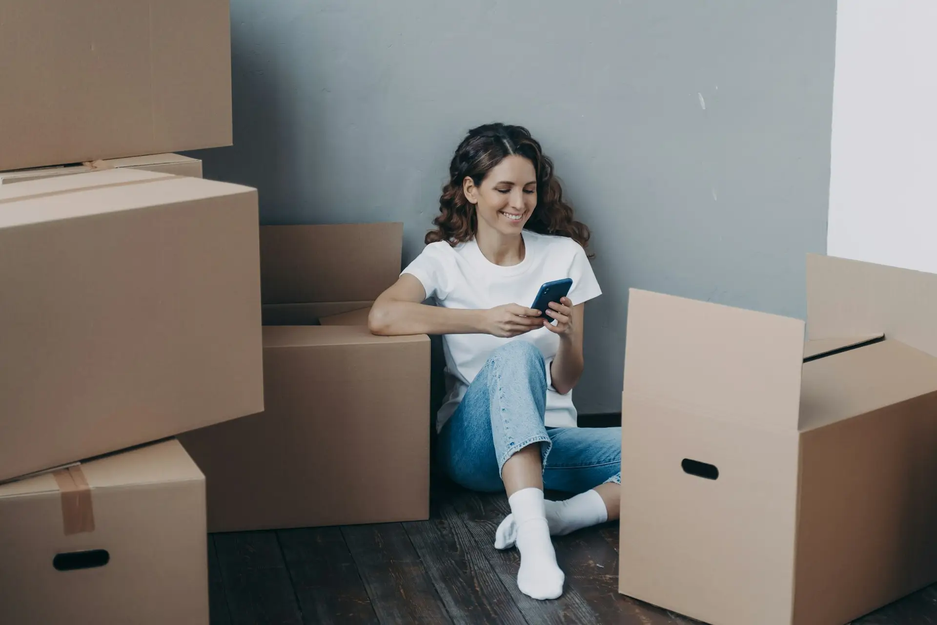 Happy girl uses phone apps, choosing relocation service, answers her mover online. Easy moving day